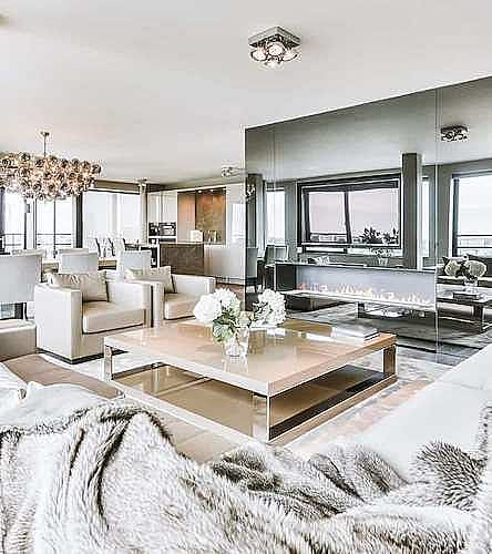 Bright living room with neutral sofas, a coffee table and large windows.